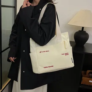 Detailed view of casual off-white canvas tote bag with shoulder strap and red print text.