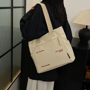 Canvas tote bag detail view, large capacity shoulder bag with stylish embroidery and pockets.