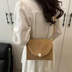 Detail view of handmade straw woven crossbody bag featuring an elegant pearl clasp and chic design.