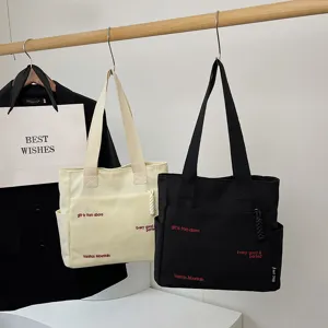 Canvas tote bag detail view, casual shoulder bag with letter print and large capacity design.