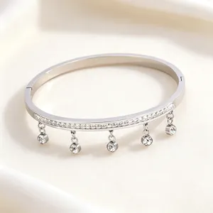 Detailed close-up of a silver titanium steel bracelet featuring paved rhinestones and hanging charms.