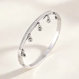 Detailed closeup of silver titanium steel diamond paved dangling charm bangle bracelet.