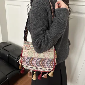 Borsa a tracolla con frange in tessuto etnico, dettagli con motivi geometrici colorati.