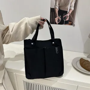 Schwarze Canvas Tragetasche Detailansicht mit mehreren Fronttaschen und robusten Griffen.
