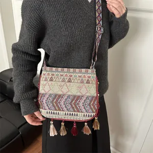 Dettaglio della borsa a tracolla tessuta etnica con tracolla geometrica e nappe.