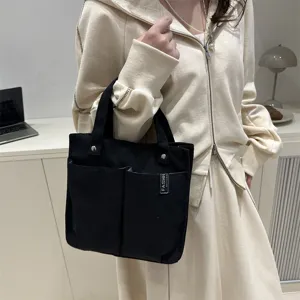Detailansicht einer schwarzen Canvas Tragetasche mit mehreren Taschen und stabilen Henkeln.
