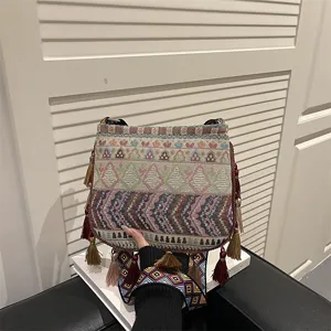 Borsa a tracolla intrecciata in stile etnico bohémien con motivi geometrici colorati e nappe.