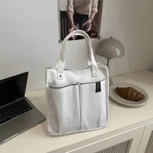 Detailansicht der weißen Canvas Tragetasche mit mehreren Taschen ideal für den Arbeitsweg.