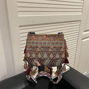 Dettaglio borsa a tracolla ricamata stile etnico, tracolla tessuta colorata e nappe.