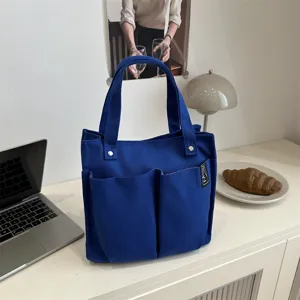 Detailansicht der blauen Segeltuch-Tragetasche mit vielen Taschen auf dem Schreibtisch.
