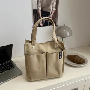 Detailaufnahme der Beigefarbenen Segeltuchtasche mit mehreren Fronttaschen und Griffen.