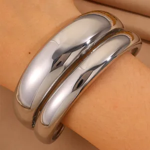 Detailed shot of wide stainless steel stacked cuff bracelets, featuring a shiny silver metal finish.