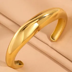 Wide stainless steel open cuff bracelet for women, trendy gold minimalist jewelry item.