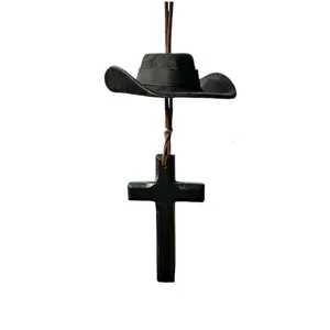 Close-up view of a retro wooden cross and miniature cowboy hat hanging ornament for car mirror.