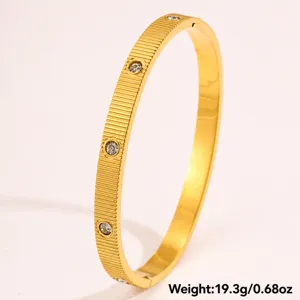 Nahaufnahme eines goldenen strukturierten Edelstahl-Armreifs mit funkelnden Zirkoniasteinen.