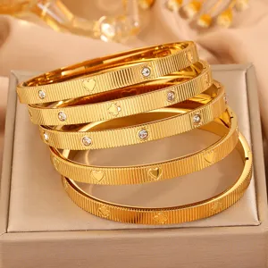 Edler Kleeblatt Armreif aus Titanstahl in Gold mit funkelnden Strasssteinen und feinem Streifen.