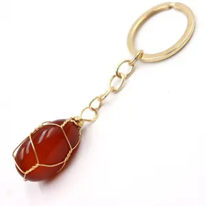Close-up of a wire-wrapped red gemstone keychain, detailed view of the gold chain and stone pendant.
