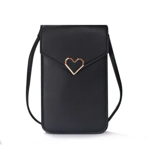 Close-up detail of the black mini crossbody phone bag with rose gold heart emblem.