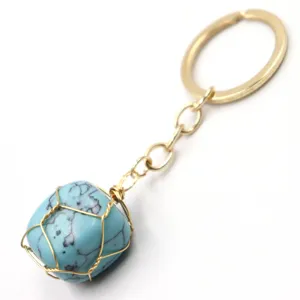 Detail view of wire wrapped turquoise stone keychain with gold ring, fashion bag accessory.