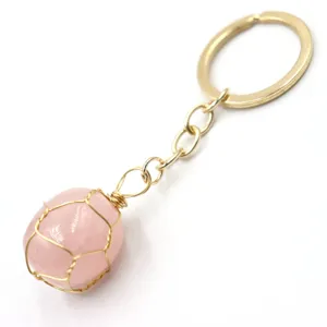 Detailed view of natural rose quartz wire-wrapped keychain with gold metal ring pendant.