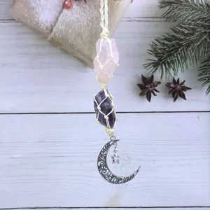 Crystal hanging ornament detail, raw pink quartz and amethyst with metal moon charm backdrop.