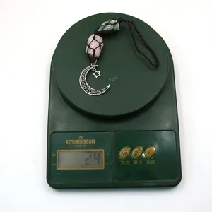 Close-up detail showing the weight of the handmade crystal pendant and moon star charm on scale.