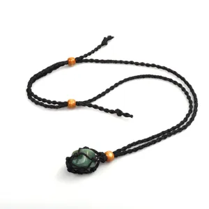 Dettaglio ravvicinato della collana con tasca a rete in corda nera che tiene un cristallo verde.