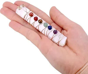Handheld natural selenite stick wrapped with colorful chakra crystal beads detail view.