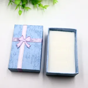 Boîte cadeau bleue avec nœud violet, idéale pour ranger en toute sécurité bagues et bijoux.