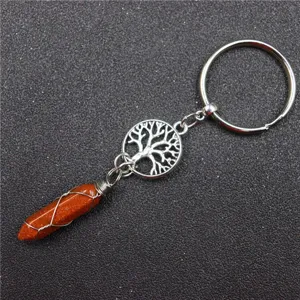 Detail view of the wire-wrapped crystal pillar and tree of life metal keychain pendant charm.