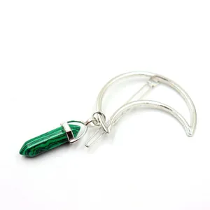 Detail view of silver crescent moon hair clip featuring a green hexagonal crystal stone.