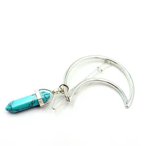 Detail shot of a silver crescent moon hair clip with a turquoise hexagonal crystal pendant.