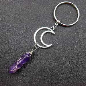 Crystal pendant keychain detail, wire-wrapped amethyst charm on textured background.