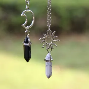 Gros plan détail de colliers pendentifs en cristal soleil et lune avec chaînes en argent.