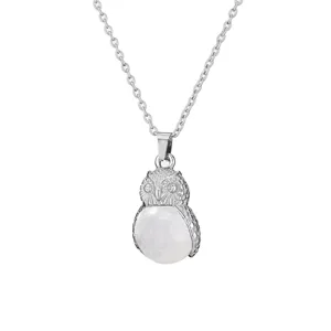 Close-up detail of silver owl pendant necklace with round white gemstone, delicate metal carving.