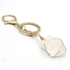 Primer plano del llavero de piedra de cristal blanco bruto con mosqueton dorado hecho mano.