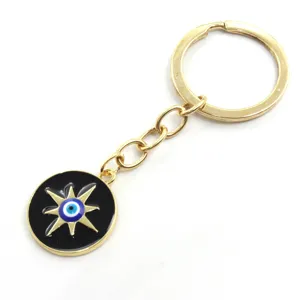 Porte-clés en alliage doré avec détail d'étoile noire et pendentif mauvais œil.