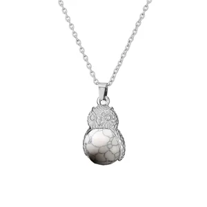 Close-up detail of silver owl pendant necklace with white textured stone bead charm.