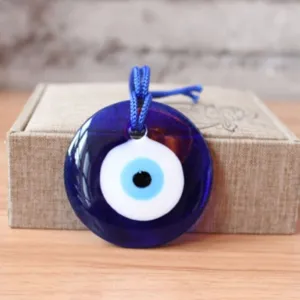 Close up detail of Turkish blue evil eye glass pendant amulet hanging on wooden background.