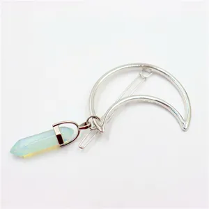 Detail shot of the crescent moon hair clip with a light blue hexagonal crystal pendant.