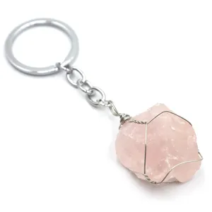 Portachiavi in cristallo di quarzo rosa grezzo avvolto in filo metallico dettaglio primo piano.
