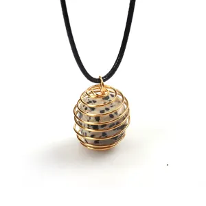 Detailansicht eines Natursteinanhängers in goldenem Drahtkäfig mit schwarzer Kette.