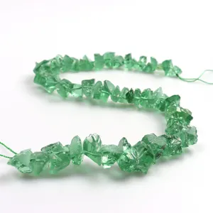 Nahaufnahme von gruenen unregelmaessigen Kristallperlen Straenge fuer DIY Schmuck Detail.