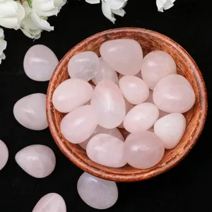 Natural rose quartz tumbled stones in wooden bowl, polished crystal for home decor and yoga.