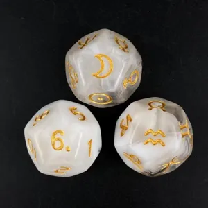 Constellation polyhedral board game dice with gold symbols on white marble texture.