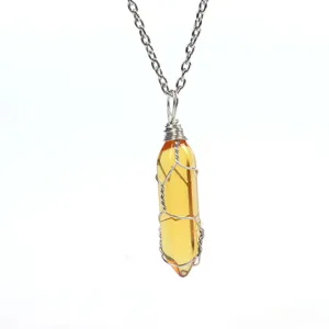 Close-up detail of yellow crystal bullet pendant with silver wire wrap and chain necklace.