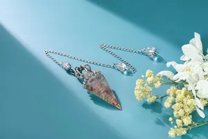 Détail de pendentif pendule en résine cristal avec forme conique hexagonale et chaîne.
