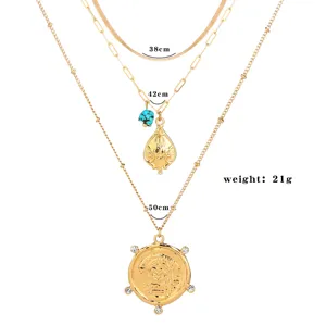 Collana a catena dorata multistrato con ciondolo a moneta e turchese per donna elegante.