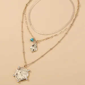 Collana multistrato dorata con ciondolo a moneta e catene delicate e di tendenza.