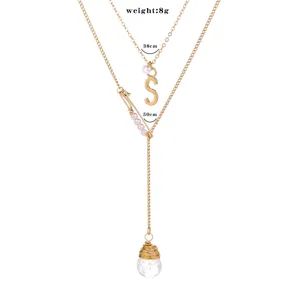 Collier double en or avec pendentif lettre S, détail de cristal et pierre naturelle.